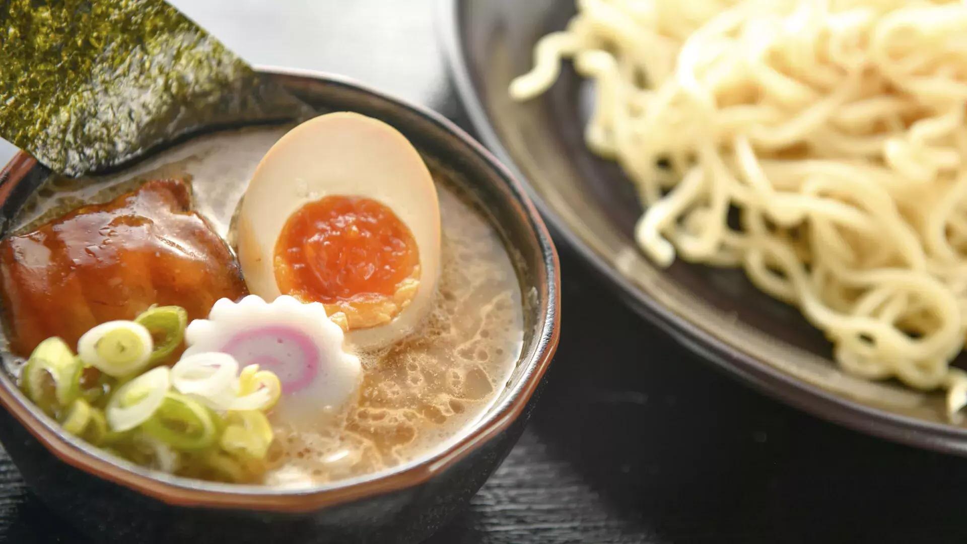 Immagine ravvicinata di una ciotola di noodles e una ciotola di zuppa di ramen con un uovo in camicia, tagliato a metà.