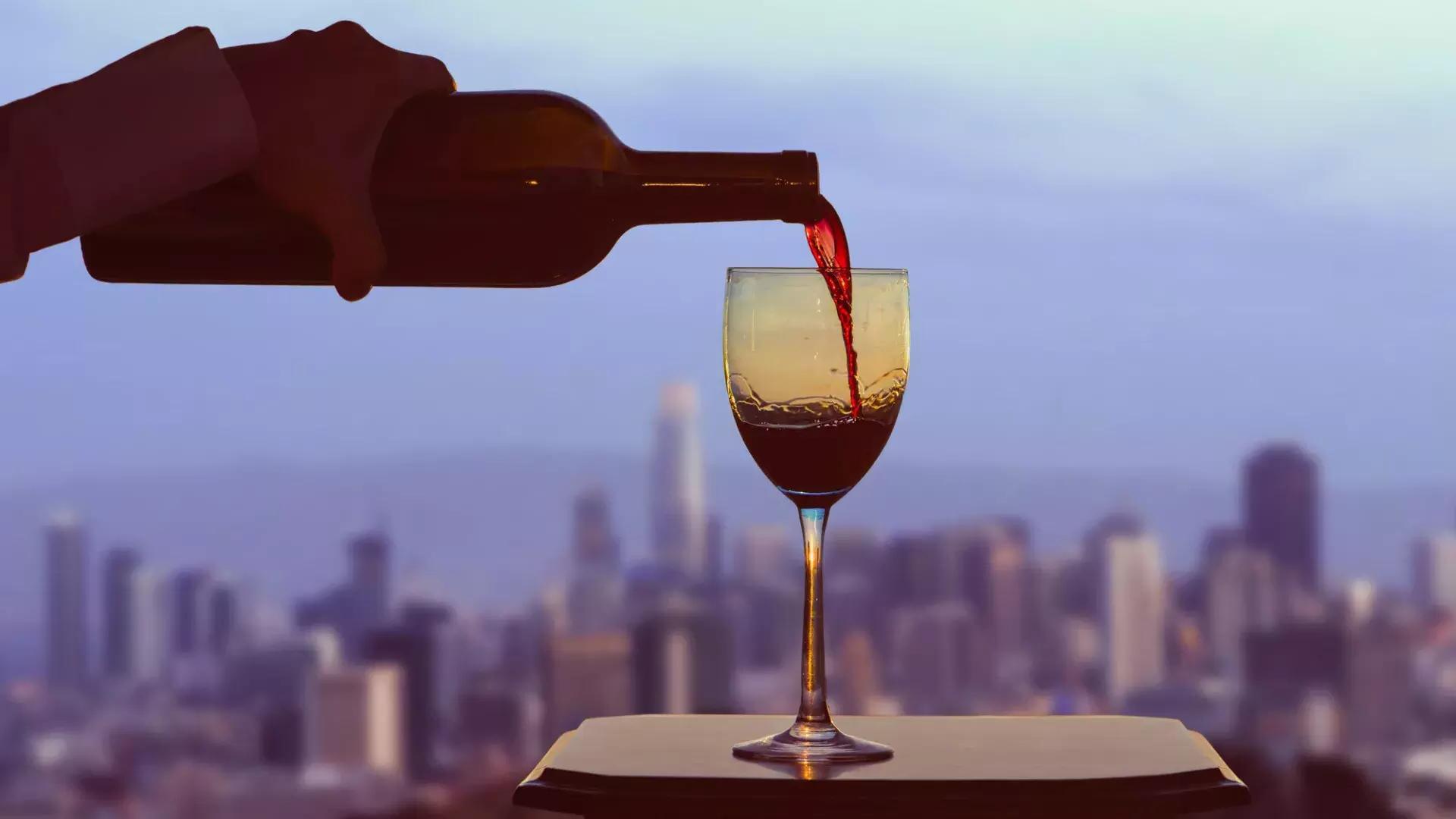 Ein Glas Rotwein wird eingeschenkt, während aus dem Fenster die Skyline von San Francisco sichtbar ist.